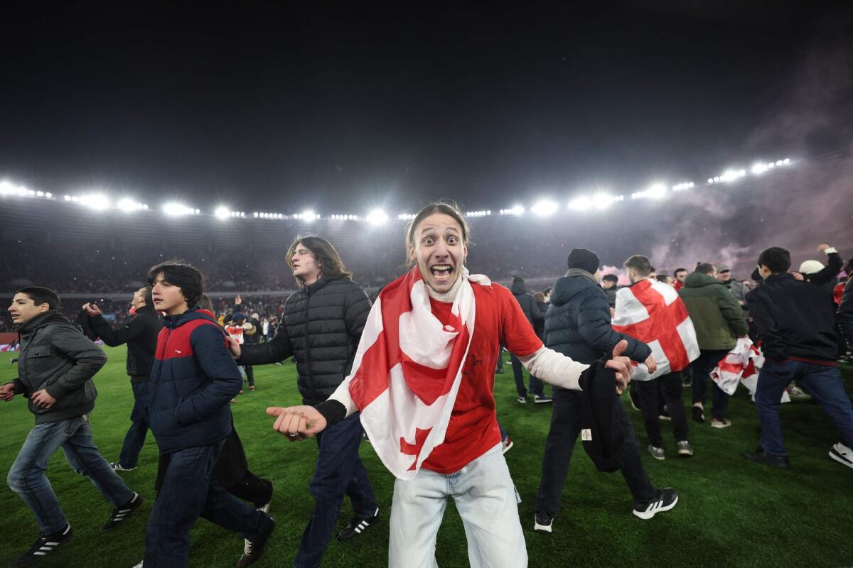 Fans celebrate on the pitch. — AFP