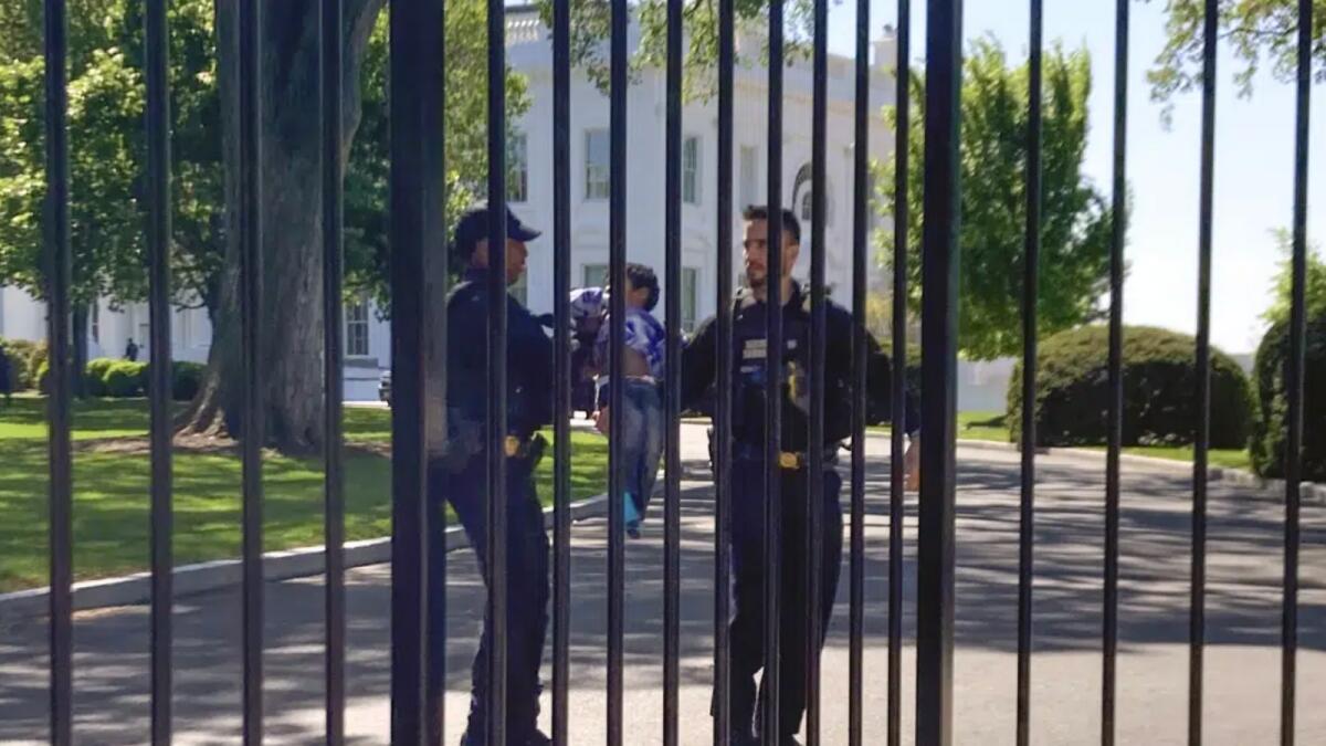 US Secret Service uniformed division police officers carry the toddler who crawled through the White House fence on Pennsylvania Avenue in Washington. — AP