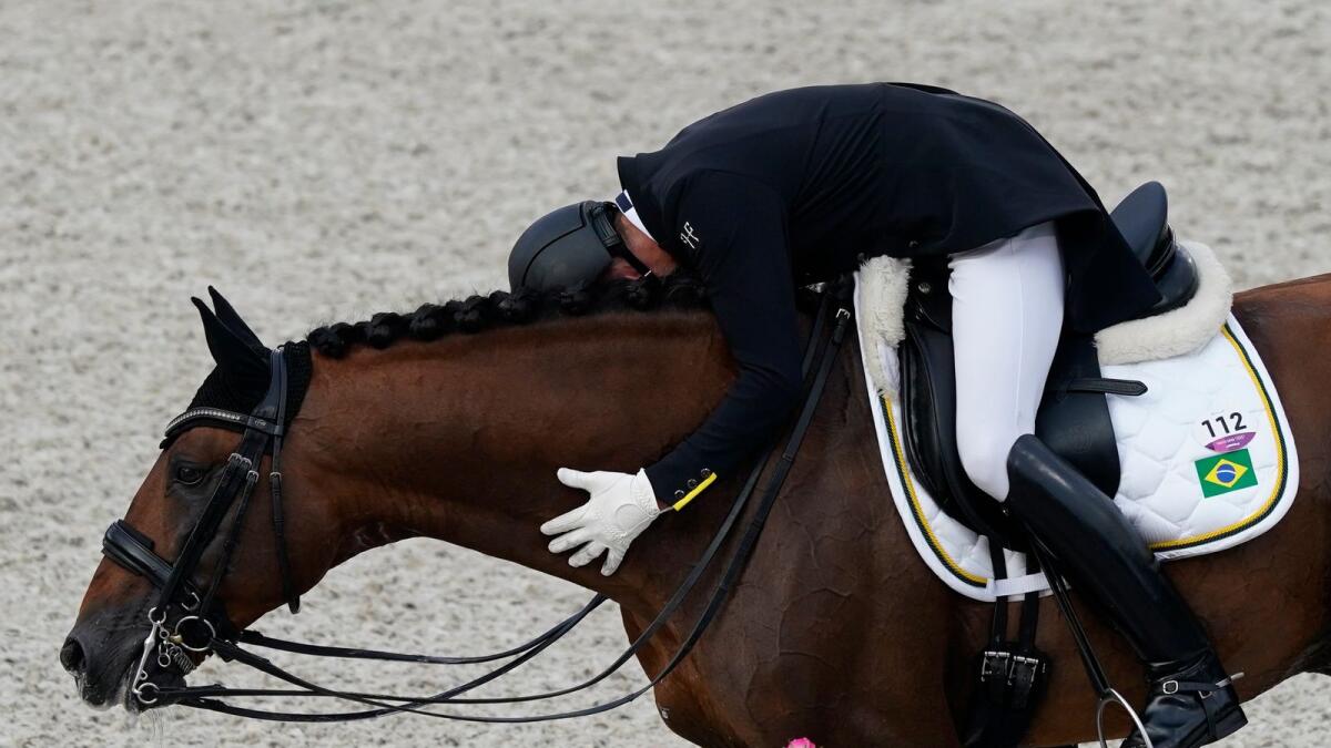 Brazil's Joao Victor Marcari Oliva, hugs Escorial Horsecampline as he celebrates after competing during the dressage Grand Prix competition at Equestrian Park the 2020 Summer Olympics. — AP