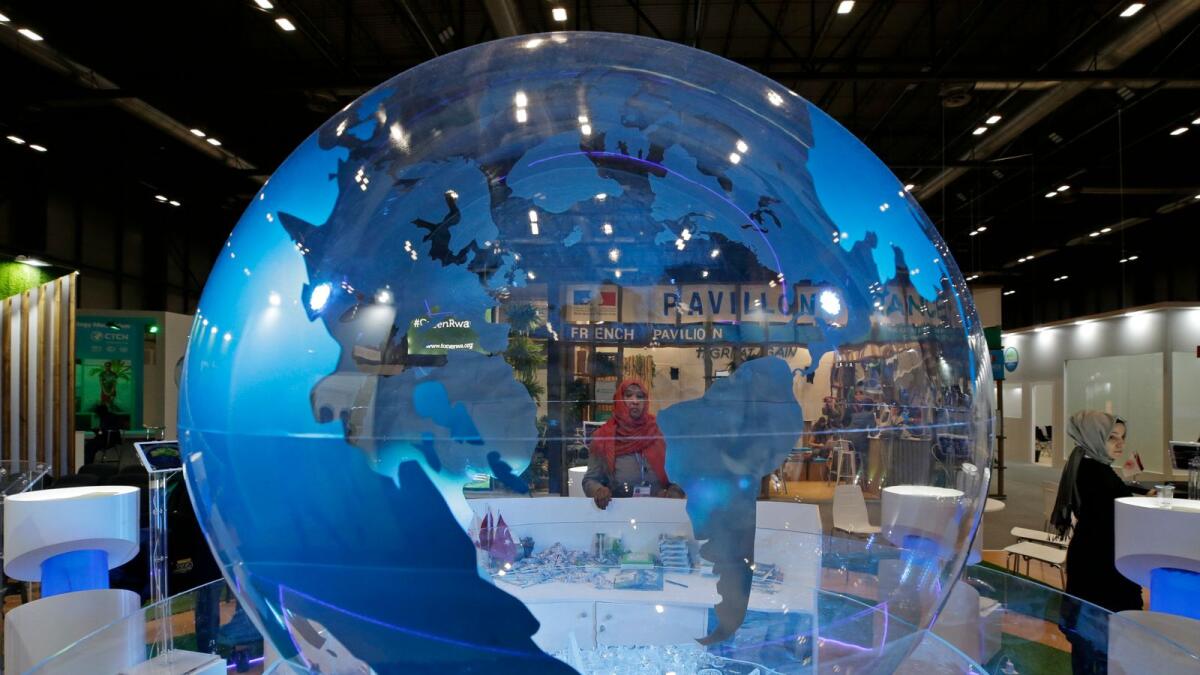 A woman looks at a World globe at the COP25 climate talks congress in Madrid. The report analysed 15 geographies in the Asia Pacific, Europe, and the Americas, and found that if global leaders unite in a systemic net-zero transition, the global economy could see new five-decade gains of $43 trillion — a boost to global GDP of 3.8 per cent in 2070. — AP file photo