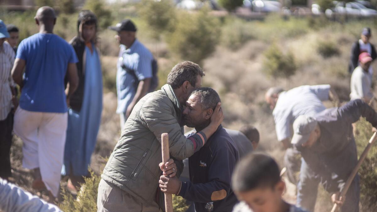 People comfort each other while digging graves for victims of the earthquake, in Ouargane village. — AP