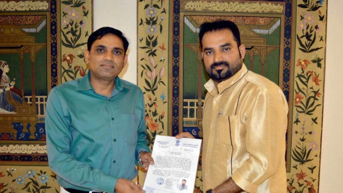 Dinesh Kumar presents a certified document authorising MM Nasar Kanhangad to work with the local authorities for repatriatiing deceased Indians back home. — Supplied photo
