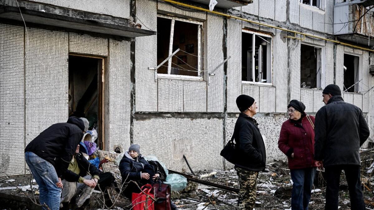People stand outside a destroyed building after bombings on the eastern Ukraine town of Chuguiv. Photo: AFP