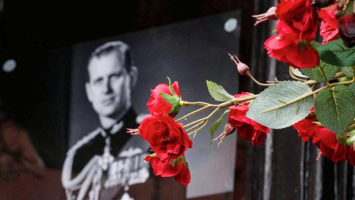 Flowers in front of a photograph of Britain's Prince Philip outside Windsor Castle in Windsor, England after the announcement regarding the death of Britain's Prince Philip. — AP