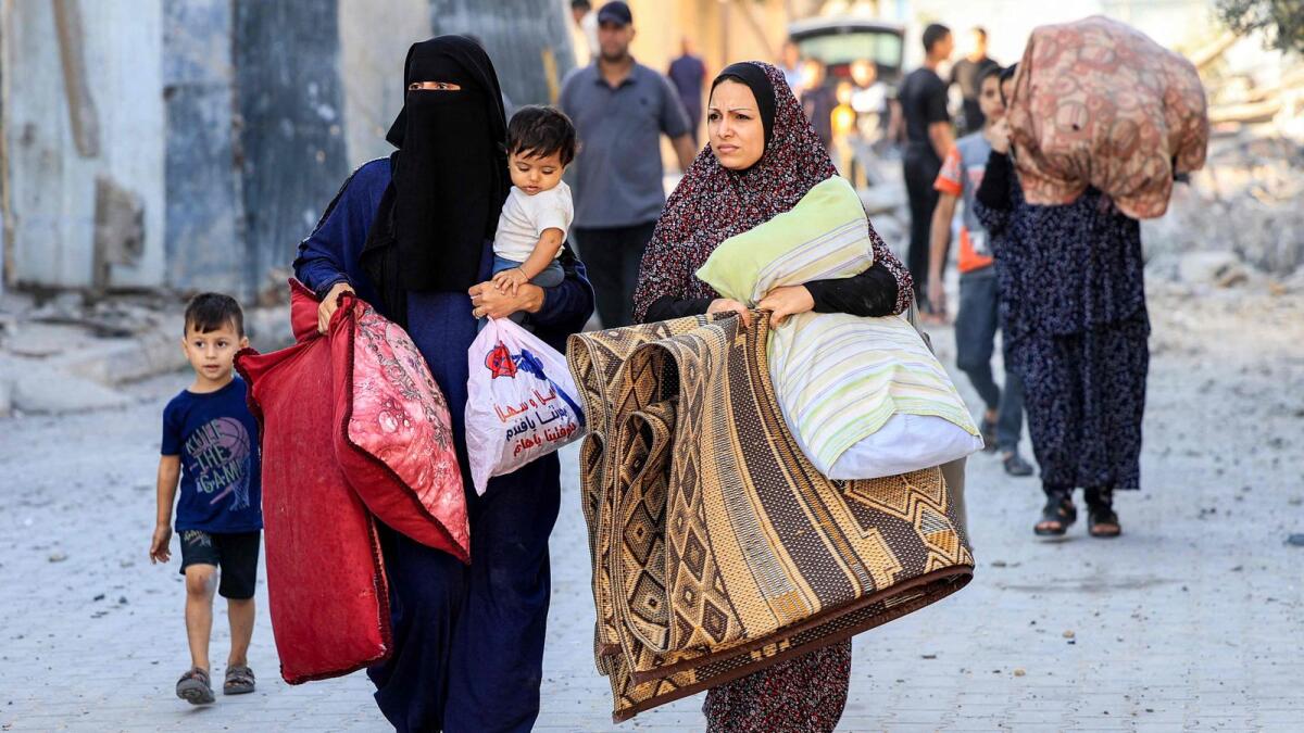 Palestinian women walk with children and their belongings as they flee an area in the aftermath of an Israeli air strike in Rafah in the southern Gaza Strip on October 13. —  AFP
