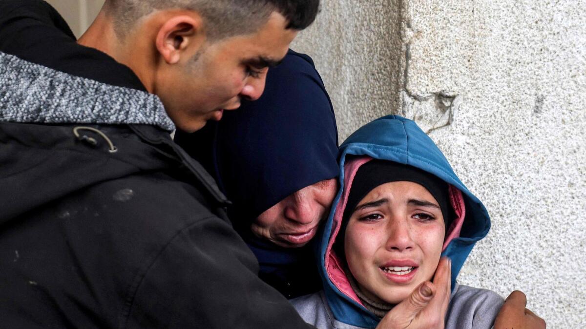 A woman and a young man embrace a crying girl as they mourn relatives who were killed during Israeli bombardment at Al Najar Hospital in Rafah in the southern Gaza Strip. — AFP