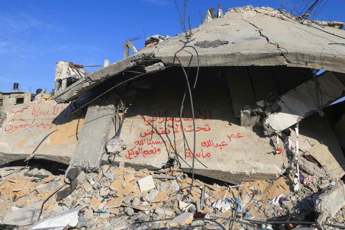 An inscription in Arabic left on a concrete slab from a destroyed building reads 'The children are still under the rubble, Omar, Abdullah, Masah', in Rafah in the southern Gaza Strip, on December 10, 2023. — AFP