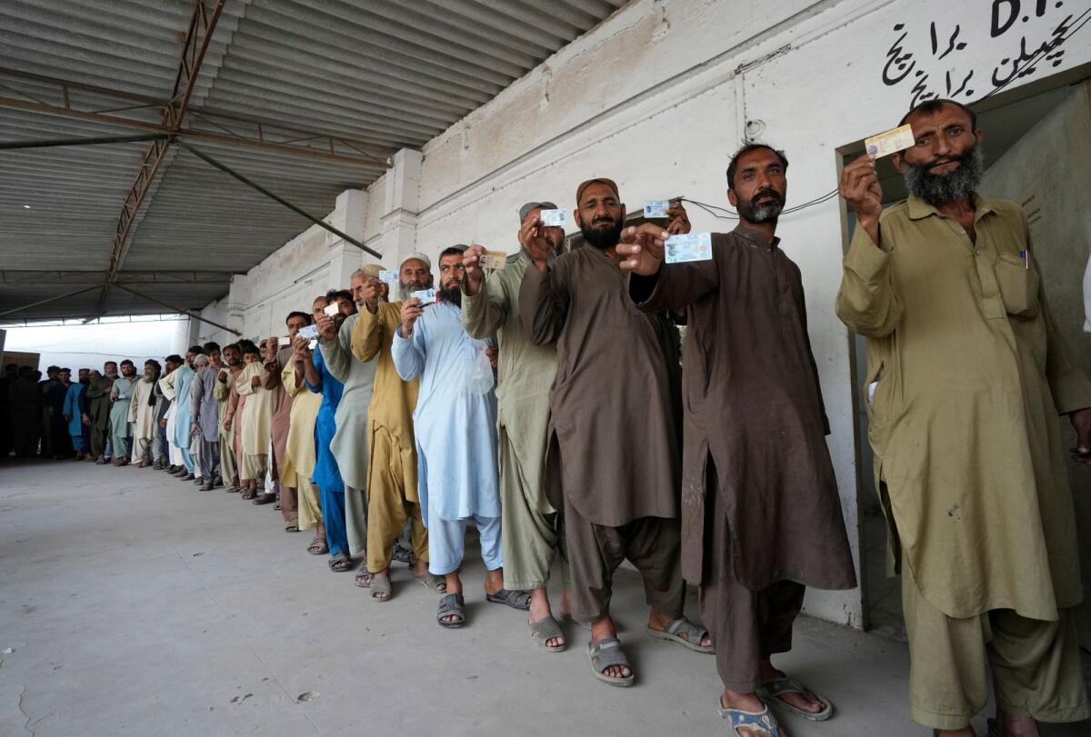 Immigrants, mostly Afghans, show their ID cards as they wait their turn to verify data at a counter of Pakistan's National Database and Registration Authority in Karachi on Tuesday. — AP