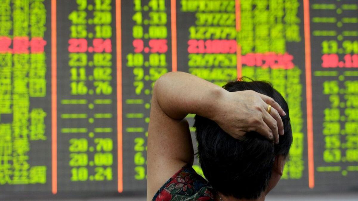 An investor looks at an electronic board showing stock information at a brokerage house in Hangzhou, Zhejiang province, China. 