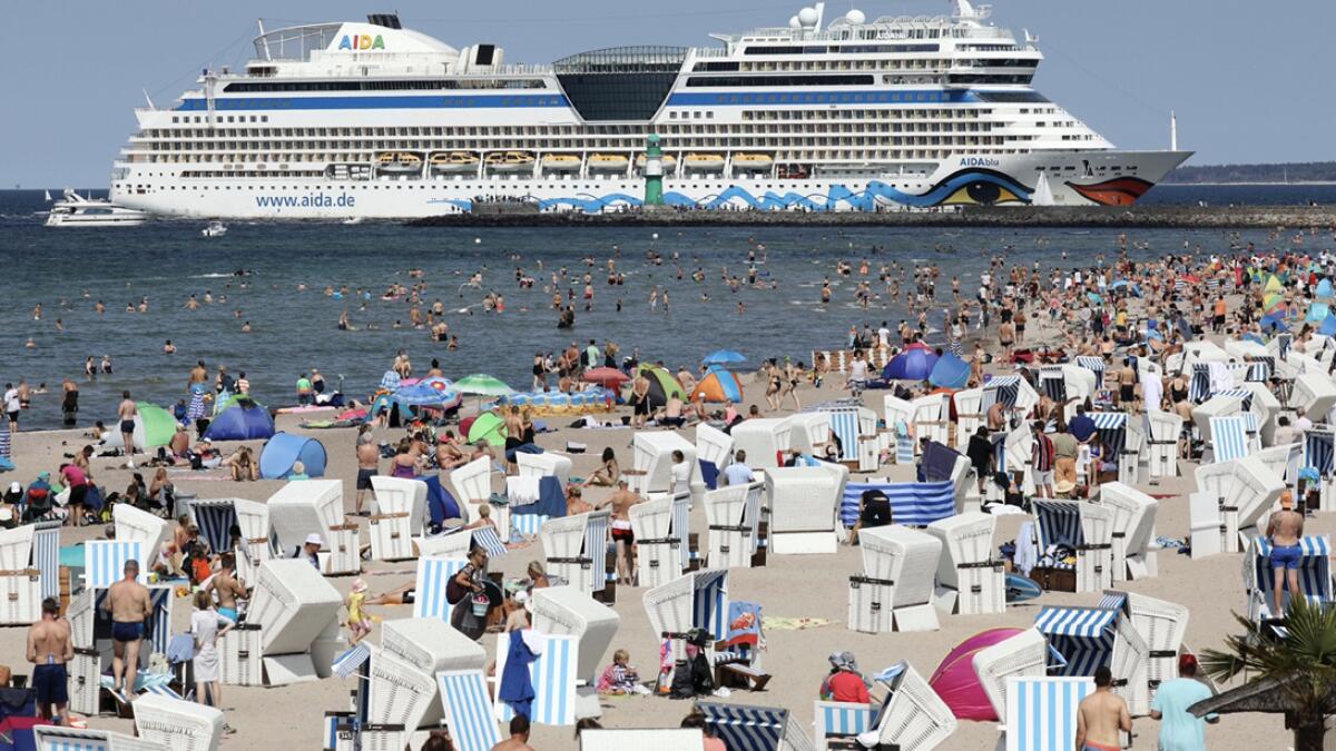 The AIDAblucrusi ship of the shipping company Aida Cruises arrives without passengers in the Baltic Sea resort, full of tourists on the beach in Rostock, Germany. The ship is one of the first cruise ships to arrive in Rostock after the start of the season, which was planned four months ago, was cancelled due to corona conditions. Photo: AP