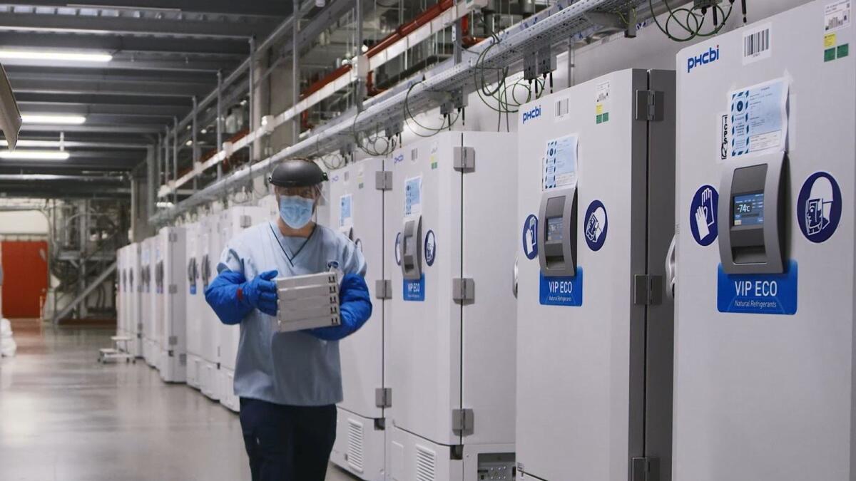 A worker passes a line of freezers holding coronavirus disease (COVID-19) vaccine candidate BNT162b2 at a Pfizer facility in Puurs, Belgium in an undated photograph.