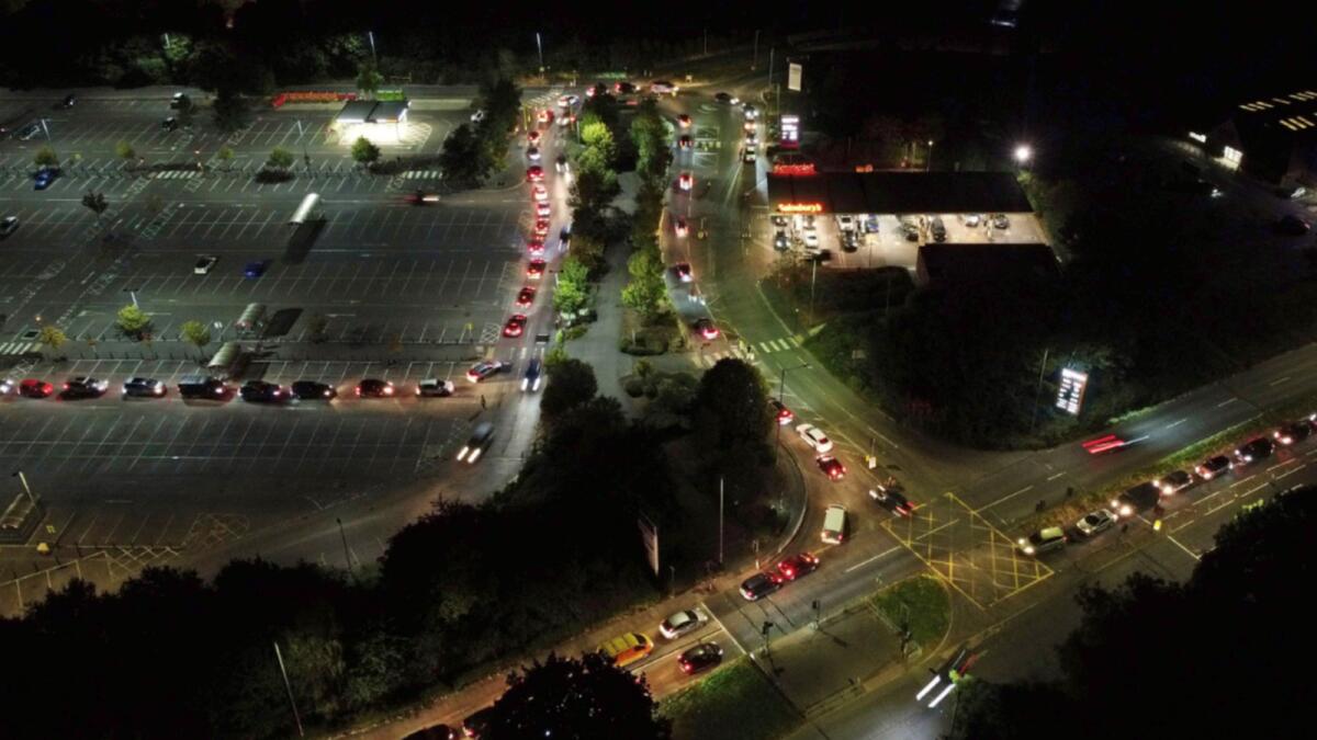 Motorists queue to fill their cars at a Sainsbury's fuel station in Ashford, England. The British government is expected to ease visa rules for truck drivers to help fix supply-chain problems that have triggered long lines at gas stations and some shuttered pumps. — AP