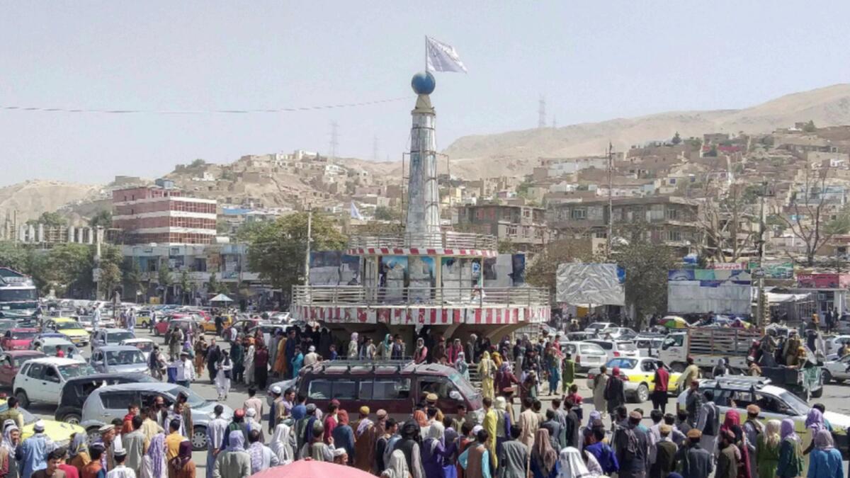 A Taliban flag is seen on a plinth with people gathered around the main city square at Pul-e-Khumri. — AFP