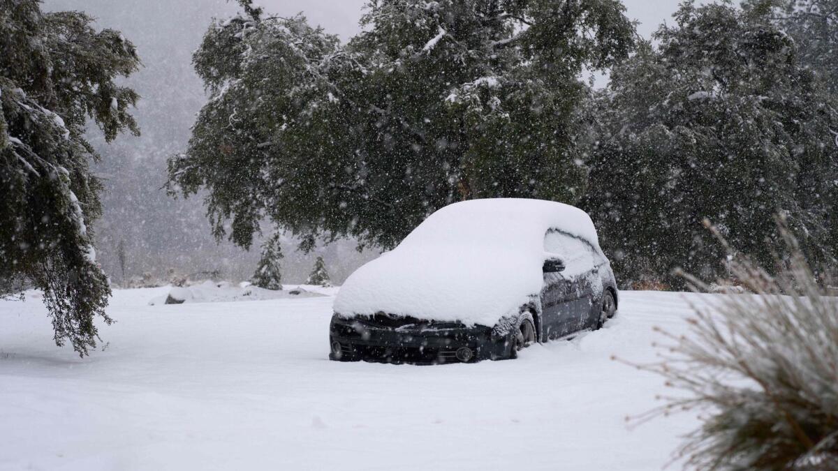 A car is covered in heavy snow in the town of Mount Baldy, California, on February 24. — AFP