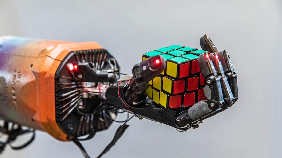 A robot hand solves a Rubik's Cube in San Francisco. Researchers at the OpenAI lab in San Francisco spent months training their robotic hand to solve the cube. (Matt Edge/The New York Times)
