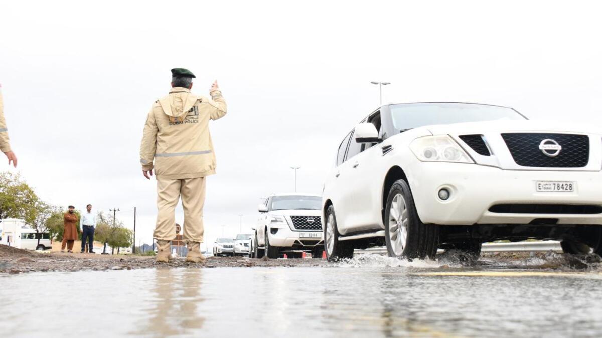 A police officer controls traffic on a water-logged street in Dubai.