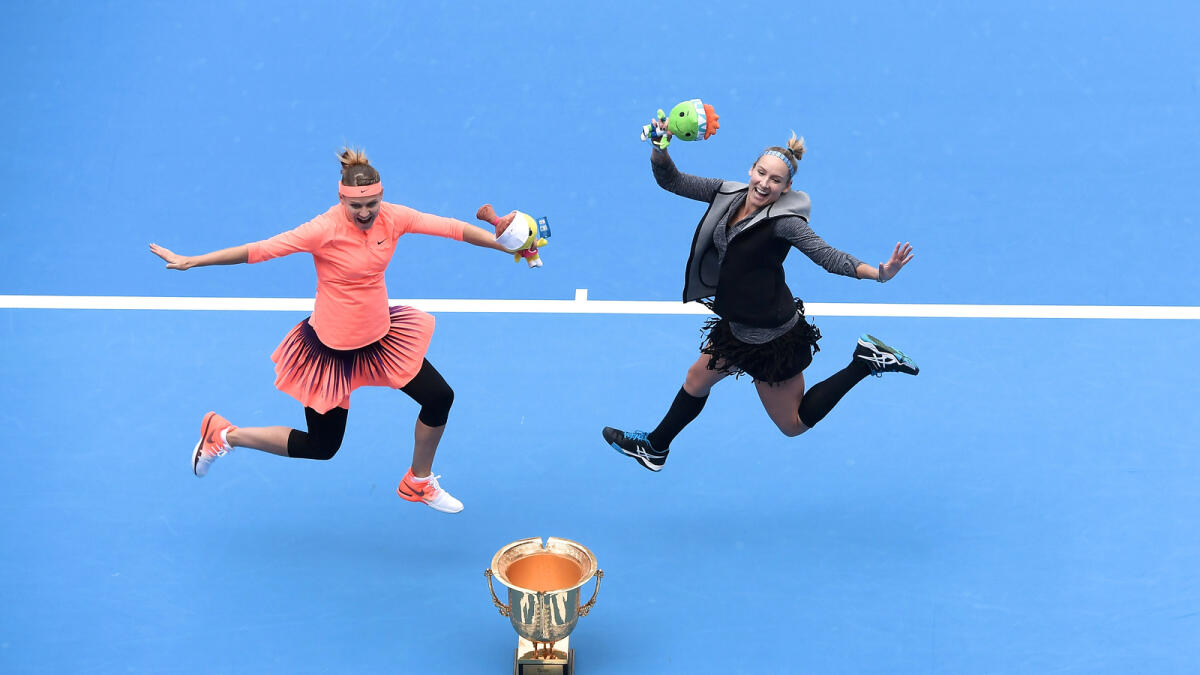Bethanie Mattek-Sands of the US and Lucie Safarova of the Czech Republic jump to pose for photos as they hold their trophy after beating France's Caroline Garcia and Kristina Mladenovic. Reuters