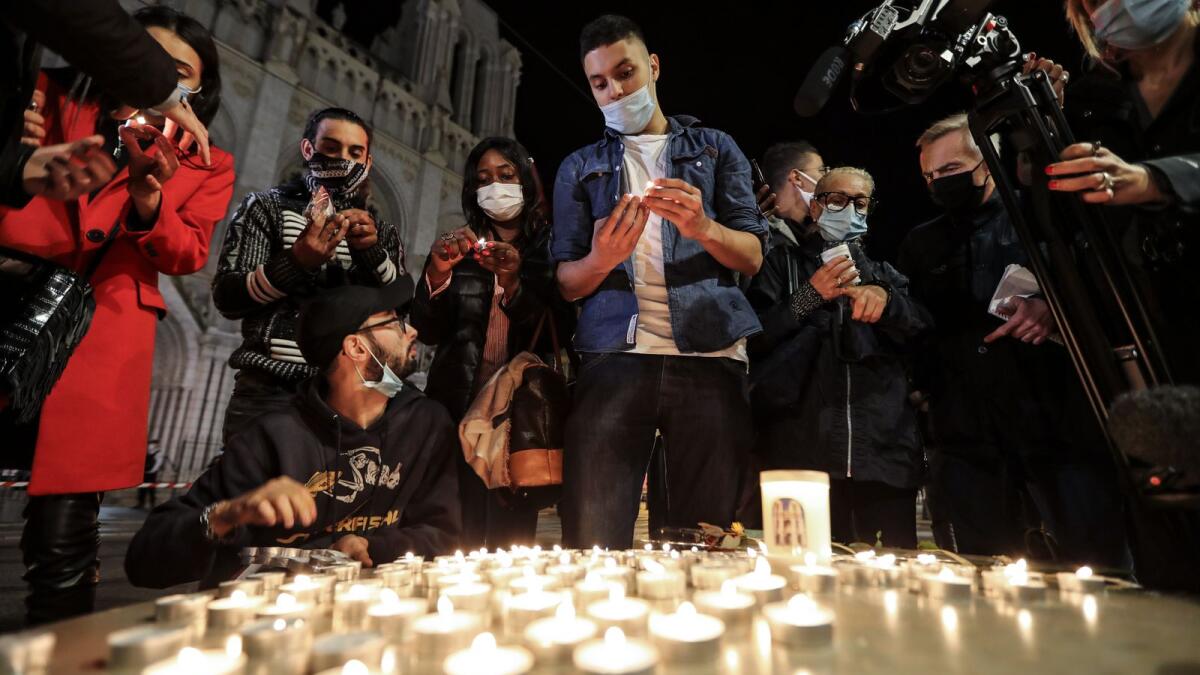 People lights candle outside the Notre-Dame de l'Assomption Basilica in Nice on October 29, 2020 in tribute to the three victims of a knife attacker, cutting the throat of at least one woman, inside the church of the French Riviera city.