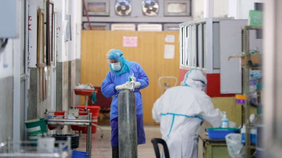 A Nepalese health worker in protective gear drags oxygen cylinder inside a Covid-19 ward at a hospital in Kathmandu. —AP