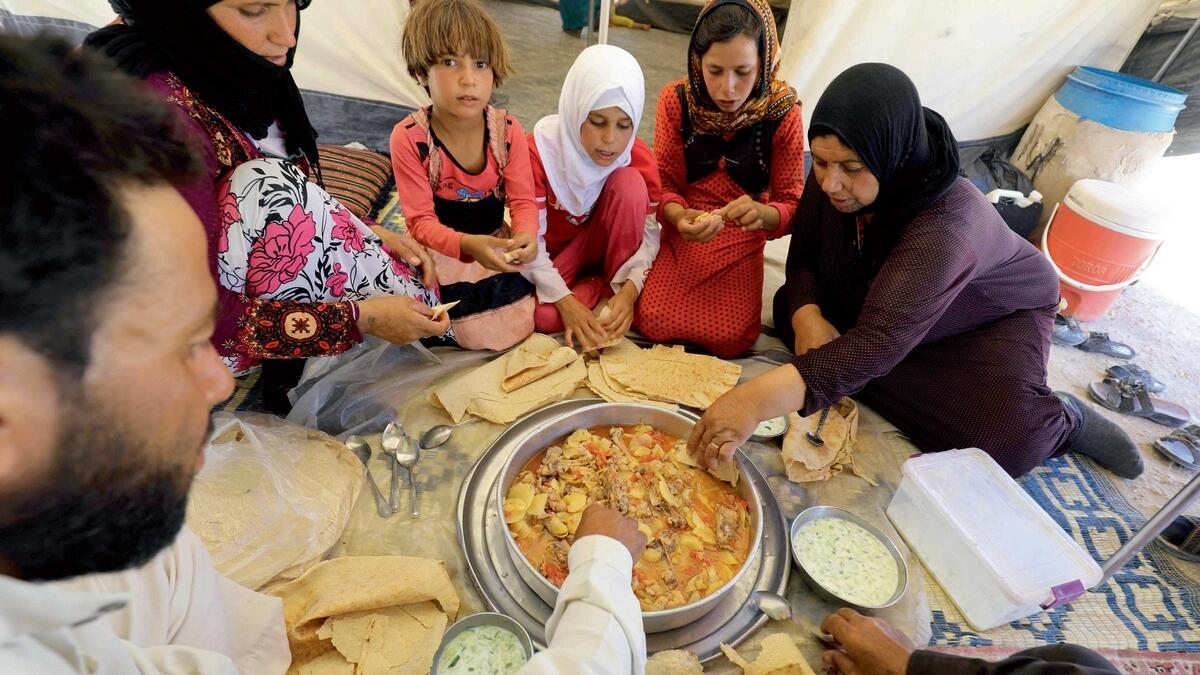A displaced Syrian family, who fled the countryside surrounding Daesh’s Syrian stronghold of Raqqa, sharing a meal at a temporary camp in the village of Ain Issa on July 11, 2017.-AFP 