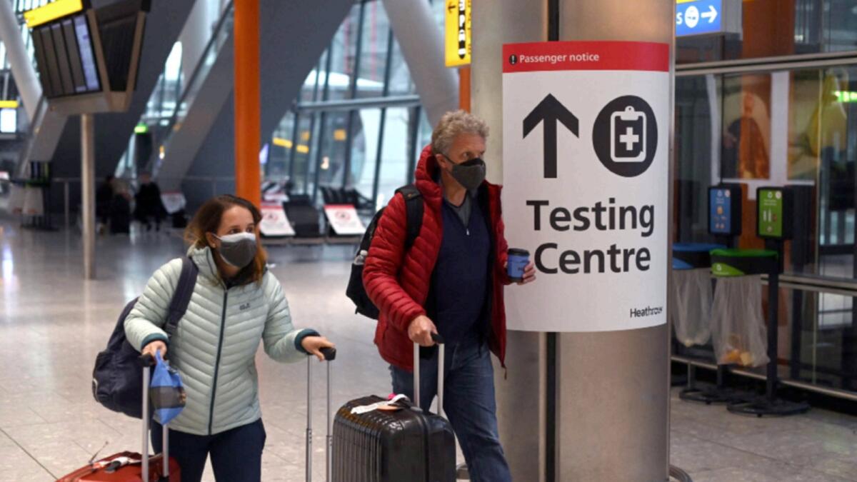 Passengers near sign for Covid-19 testing centre at London Heathrow airport. — AFP