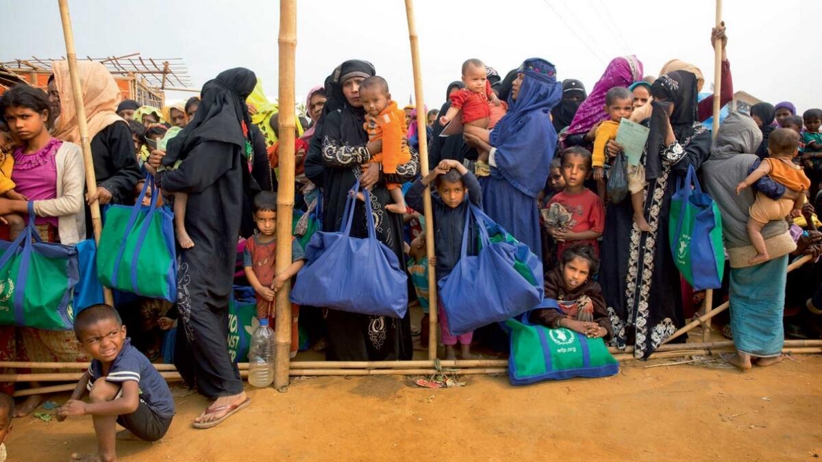Rohingya Muslim women with their children stand in a queue outside a food distribution centre at Balukhali refugee camp 50km from Cox’s Bazar in Bangladesh. — AP