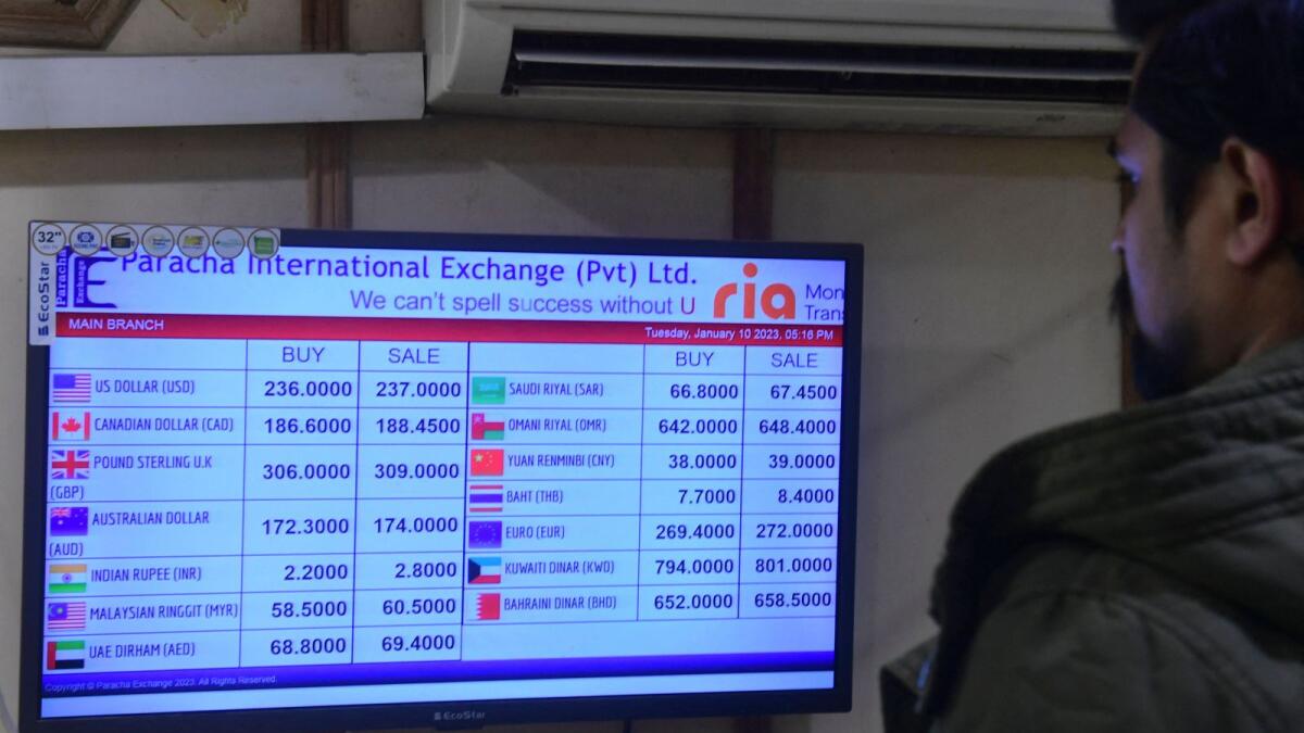 Aman checks foreign currency rates displayed on a monitor at a money exchange market in Karachi. - AFP