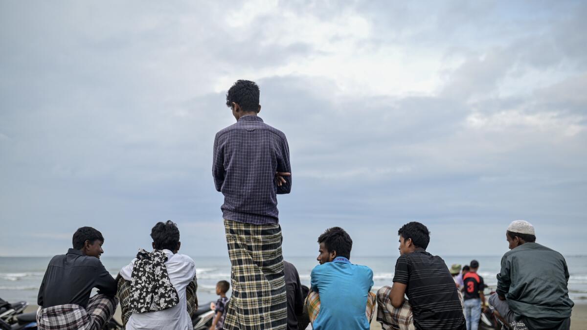 Ethnic Rohingya men chat on the beach where they landed in Pidie, Indonesia. — AP