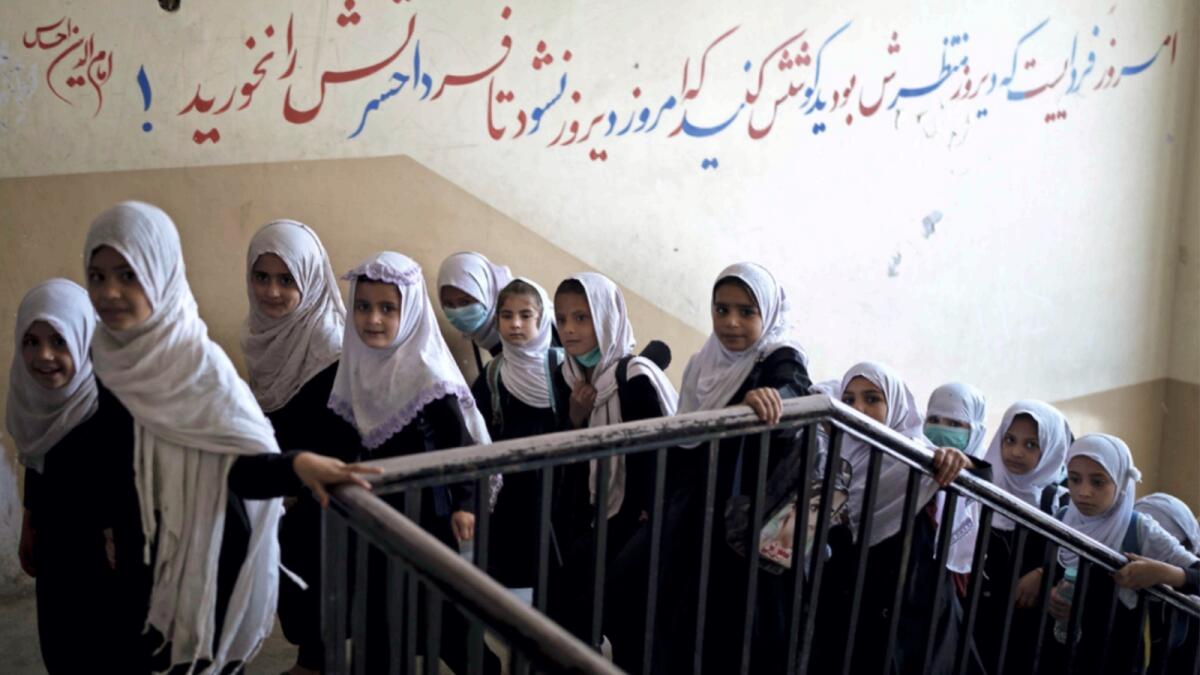 Girls walk upstairs as they enter a school before class in Kabul. — AP