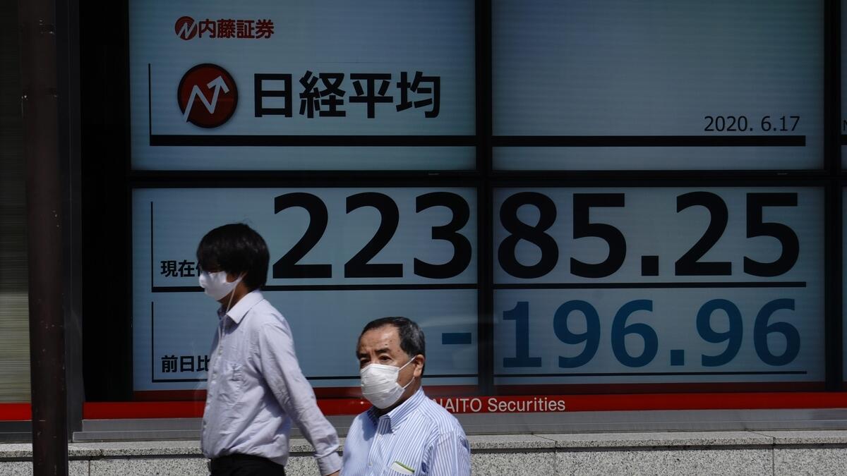 Men walk in front of an electronic stock board showing Japan's Nikkei 225 index at a securities firm in Tokyo on Wednesday. -  AP