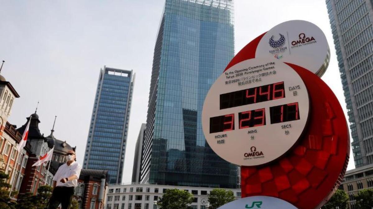 A man wearing a protective mask walks past a countdown clock for the Tokyo 2020 Olympic Games. (Reuters)