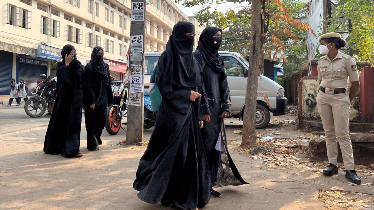 Students wearing hijab arrive to attend classes as a policewoman stands guard outside a government girls school in Udupi town in the southern state of Karnataka. Photo: Reuters file