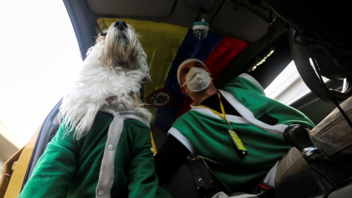 Nicolas Walteros, 52, sits inside a taxi with his dog Colonel using Santa's hats, amid the spread of the coronavirus disease (COVID-19) pandemic in Bogota, Colombia December 23, 2020. Picture taken December 23, 2020.