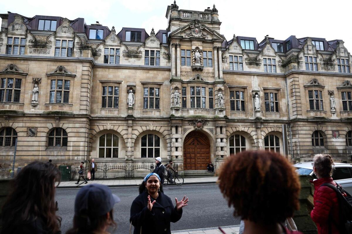 Tour guide Devika talks with a group of people attending an 'Uncomfortable Oxford' tour outside the Rhodes Building, in Oxford, on October 20, 2023. — AFP