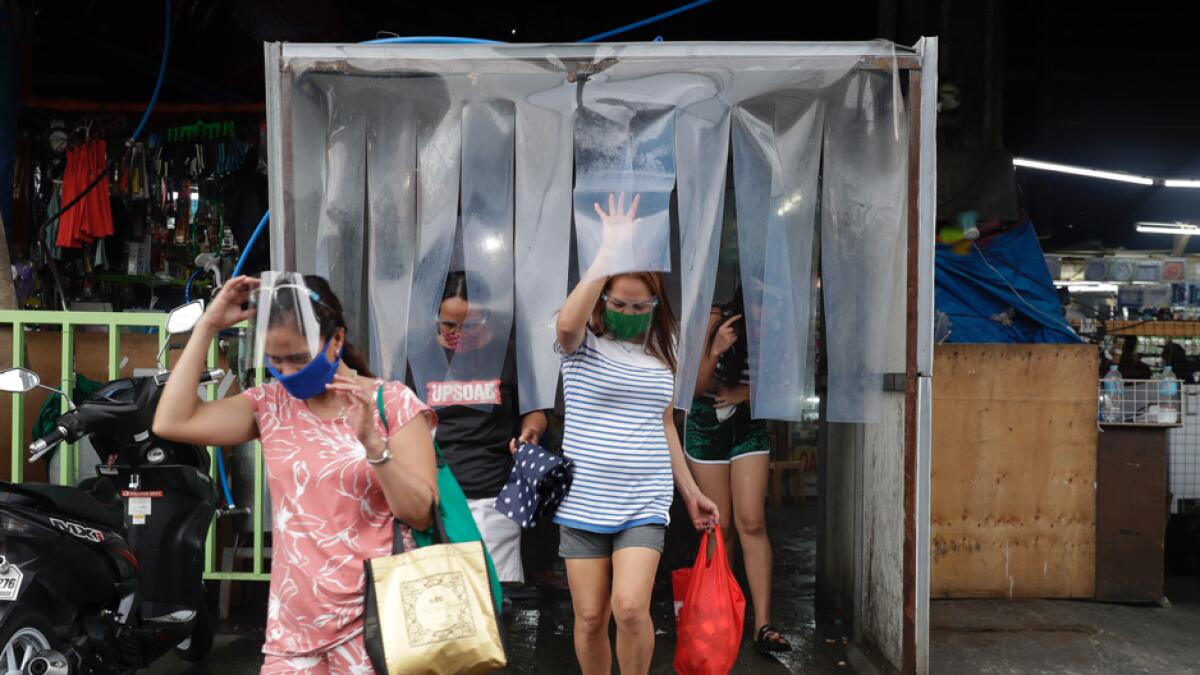 Women exit from a disinfecting area after buying food at a public market in preparation for stricter lockdown measures in Quezon city, Philippines. Photo: AP