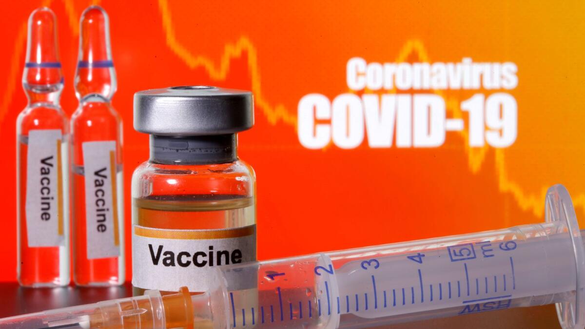 FILE PHOTO: Small bottles labelled with 'Vaccine' stickers stand near a medical syringe in front of displayed 'Coronavirus COVID-19' words in this illustration taken April 10, 2020. REUTERS/Dado Ruvic/Illustration/File Photo