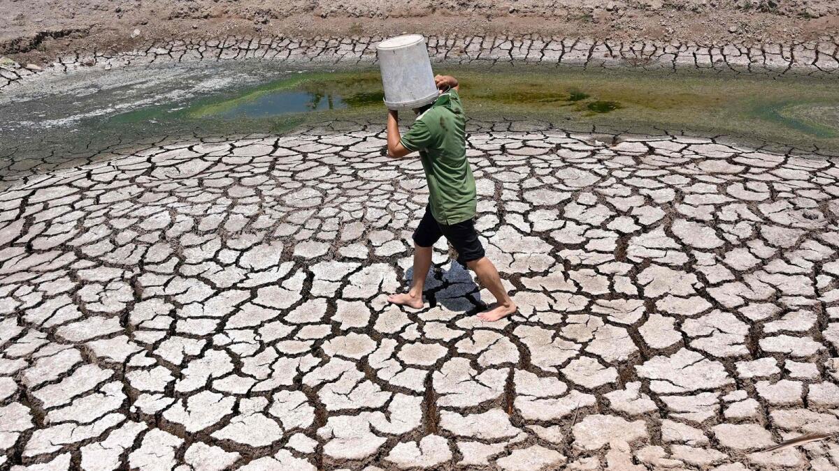 A man carries a plastic bucket across the cracked bed of a dried-up pond in Vietnam's southern Ben Tre province. Europe's climate monitor said on Tuesday that March was the hottest on record.  — AFP