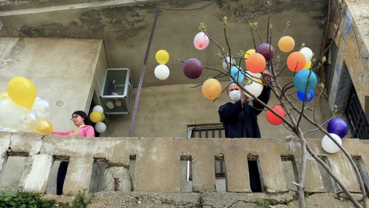 A man hangs balloons on a tree to celebrate Easter in the town of Jezzine, southern Lebanon. Photo: Reuters