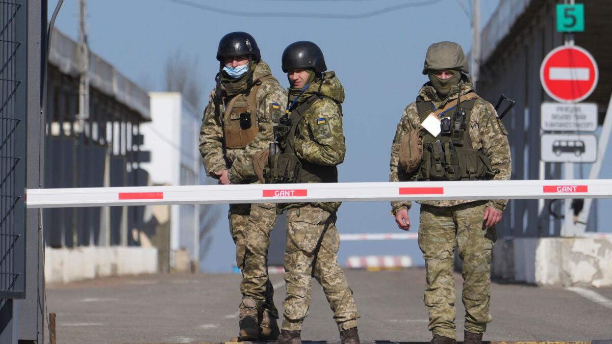 Ukrainian border guards stand at a checkpoint from territory controlled by Russia-backed separatists to the territory controlled by Ukrainian forces in Novotroitske. (AP)