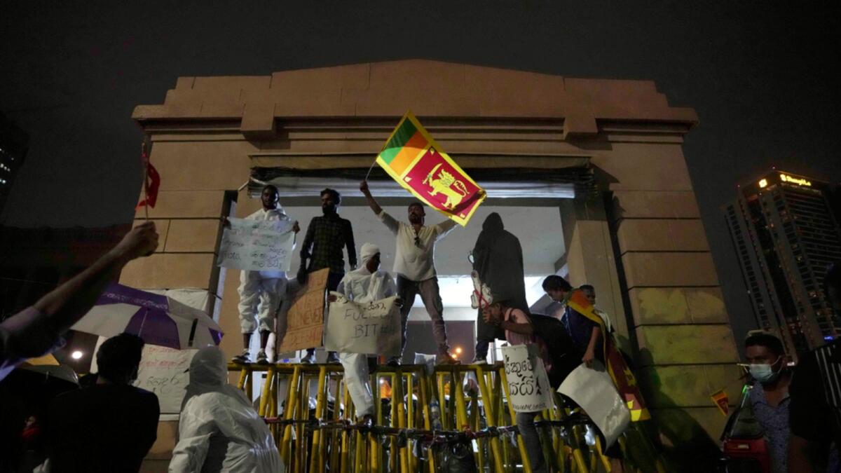 Sri Lankans shout anti government slogans blocking the entrance to president's office during a protest in Colombo. — AP