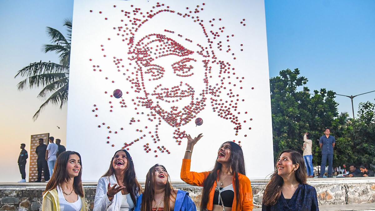 Women pose for photographs in front of an art installation of Virat Kohli, made from cricket balls, on his birthday in Mumbai, Saturday. — PTI