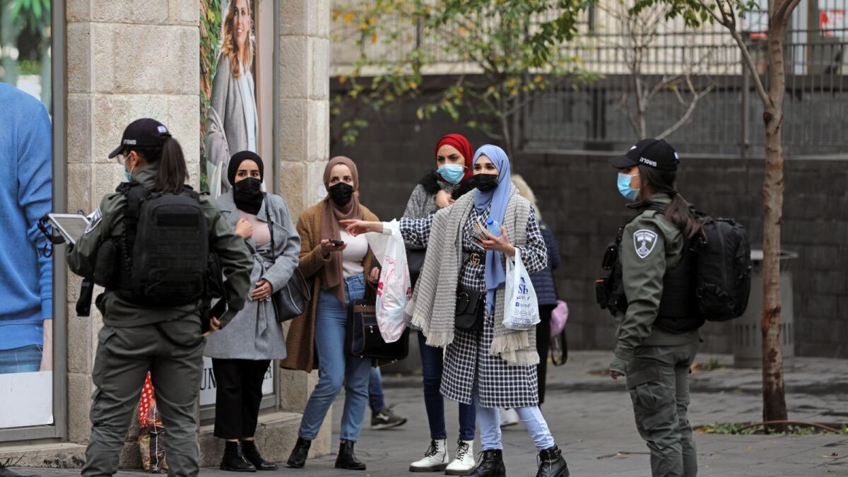 Women wearing protective face masks have their details checked by Israeli border policewomen in Jerusalem December 24, 2020.