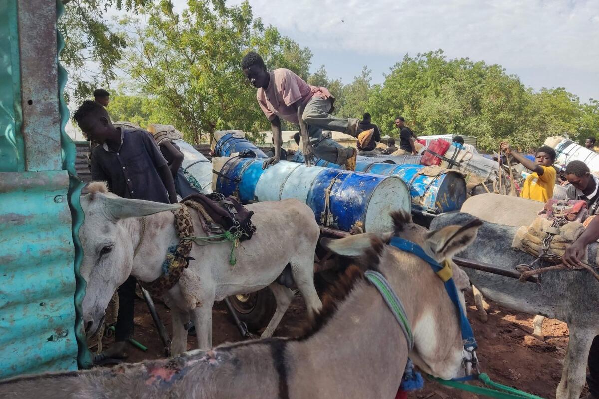 People use makeshift donkey-drawn tanks to re-supply with water as traders and donkey farmers gather in an open market in Gedaref state in eastern Sudan on February 16, 2024. — AFP
