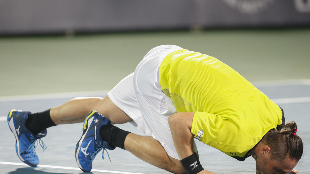 Marcos Baghdatis kisses the court after rallying to beat Spain’s Feliciano Lopez in the men’s singles semifinals in the Dubai Duty Free Tennis Championships on Friday. 