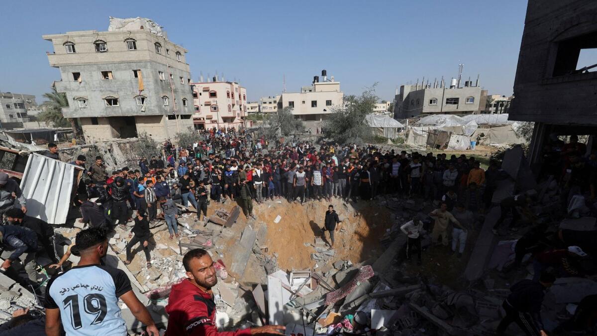 Palestinians gather as others search for casualties at the site of an Israeli strike on a house in Rafah on November 23. — Reuters