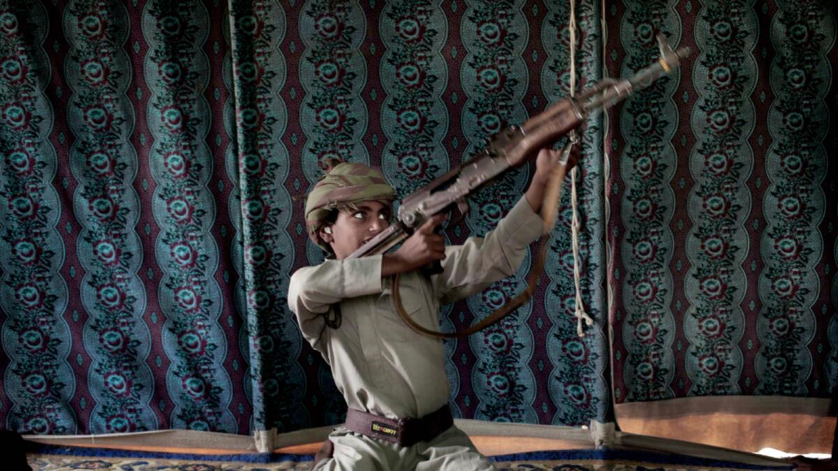 A 12-year-old former child soldier with Houthi rebels demonstrates how to use a weapon at a camp for displaced person. — AP