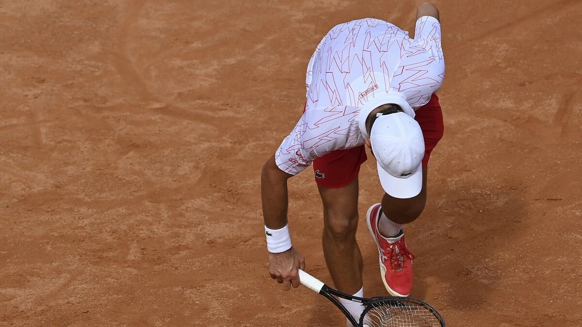 Serbia's Novak Djokovic checks his broken racket during is match with Germany's Dominik Koepfer during their quarterfinals at the Italian Open tennis tournament