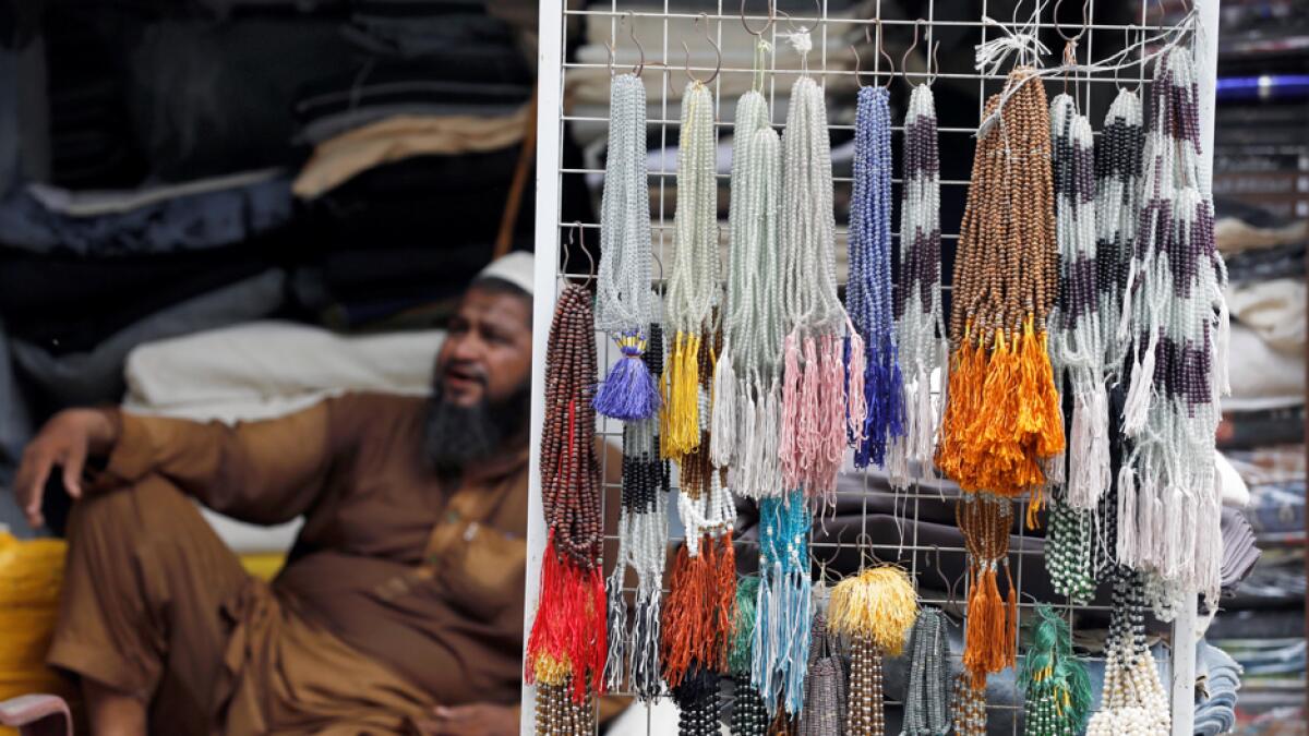 A shopkeeper sits beside prayer bead samples, which are sold during the annual Haj pilgrimage season, as he waits for customers along a wholesale market as the spread of the coronavirus disease continues, in Karachi, Pakistan. Photo: Reuters