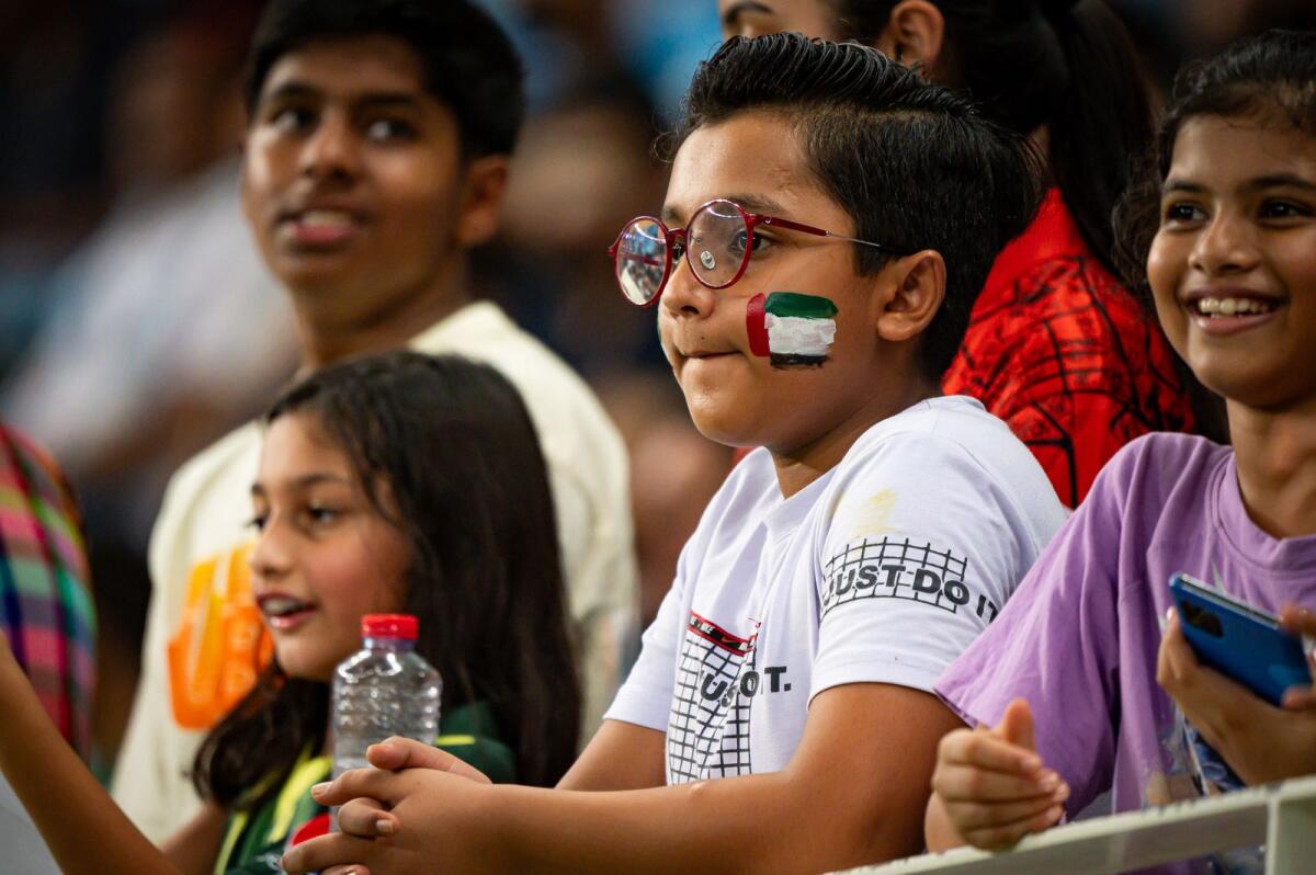 A kid with UAE flag painted on face watch the action.