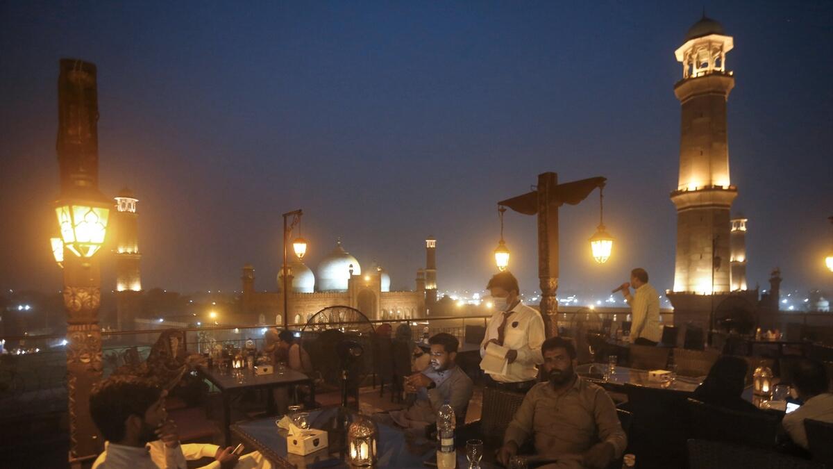 People eat at a rooftop restaurant close to historical Badshahi Mosque, in back, following an ease in restrictions that had been imposed to help control the coronavirus, in Lahore, Pakistan. Pakistan's daily virus infection rate has stayed under 1,000 for more than four weeks prompting the government to further ease restrictions for restaurants, parks, gyms and cinemas. Photo: AP